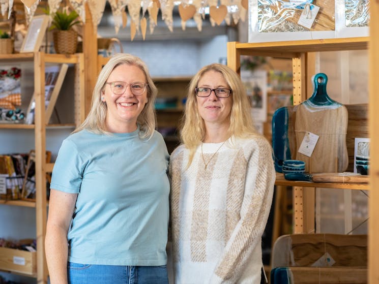 Two blonde women wearing glasses smiling in a store