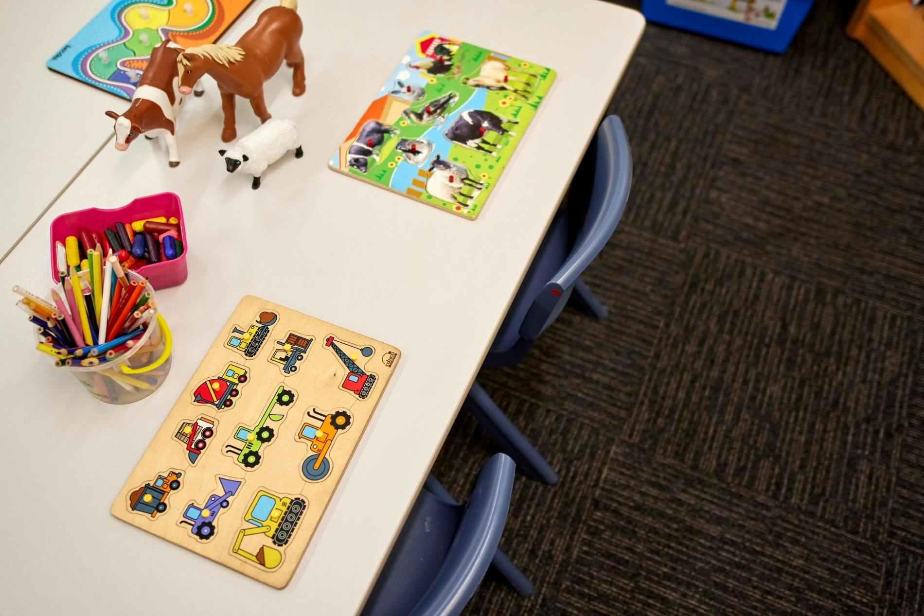 子供用サイズのテーブルに置かれた木製のパズルと動物の置物。