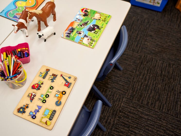 Wooden puzzles and animal figurines on a child sizes table.
