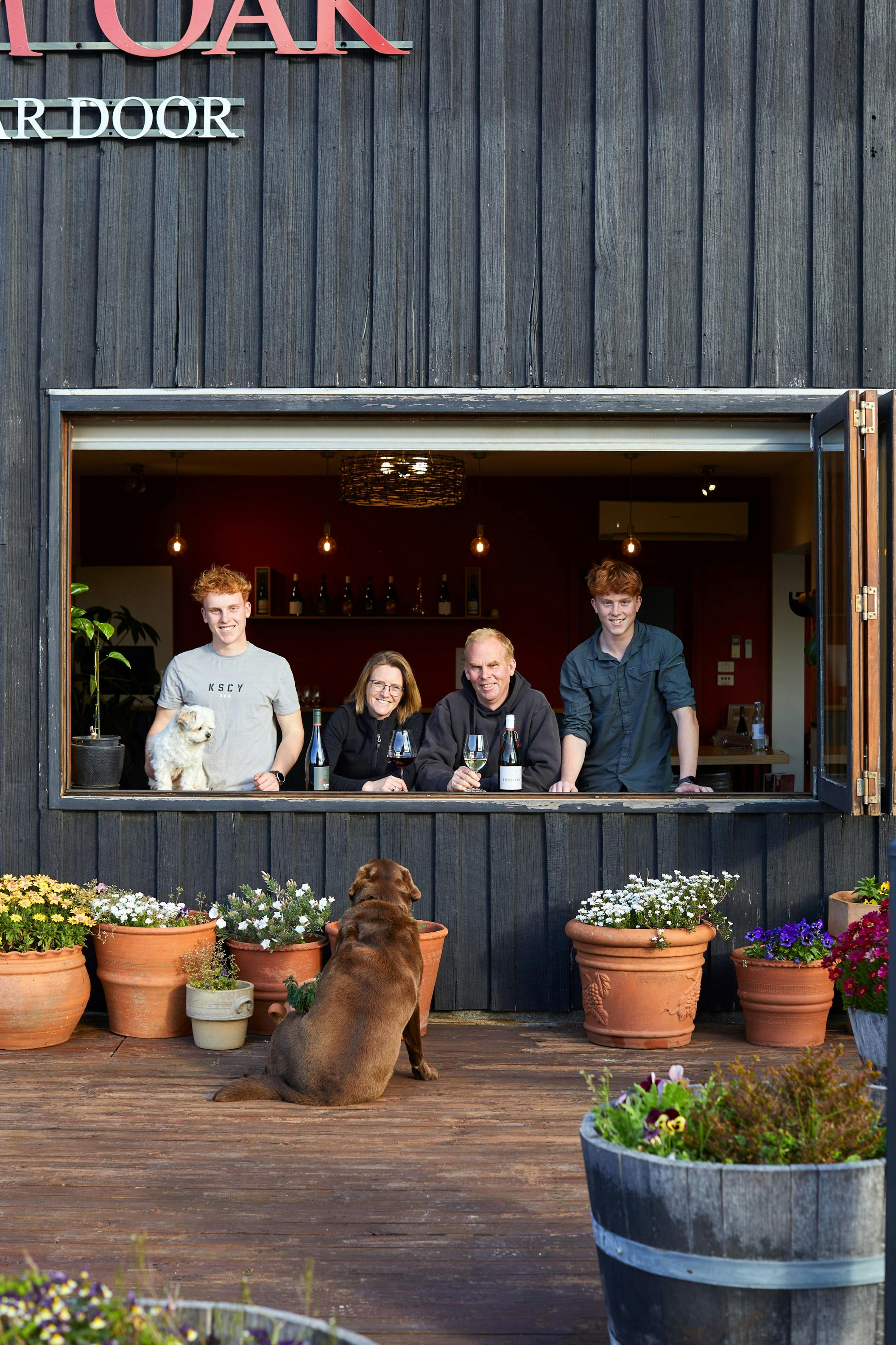 Family photo of two teenage boys on either side of their parents and a small dog in an open window