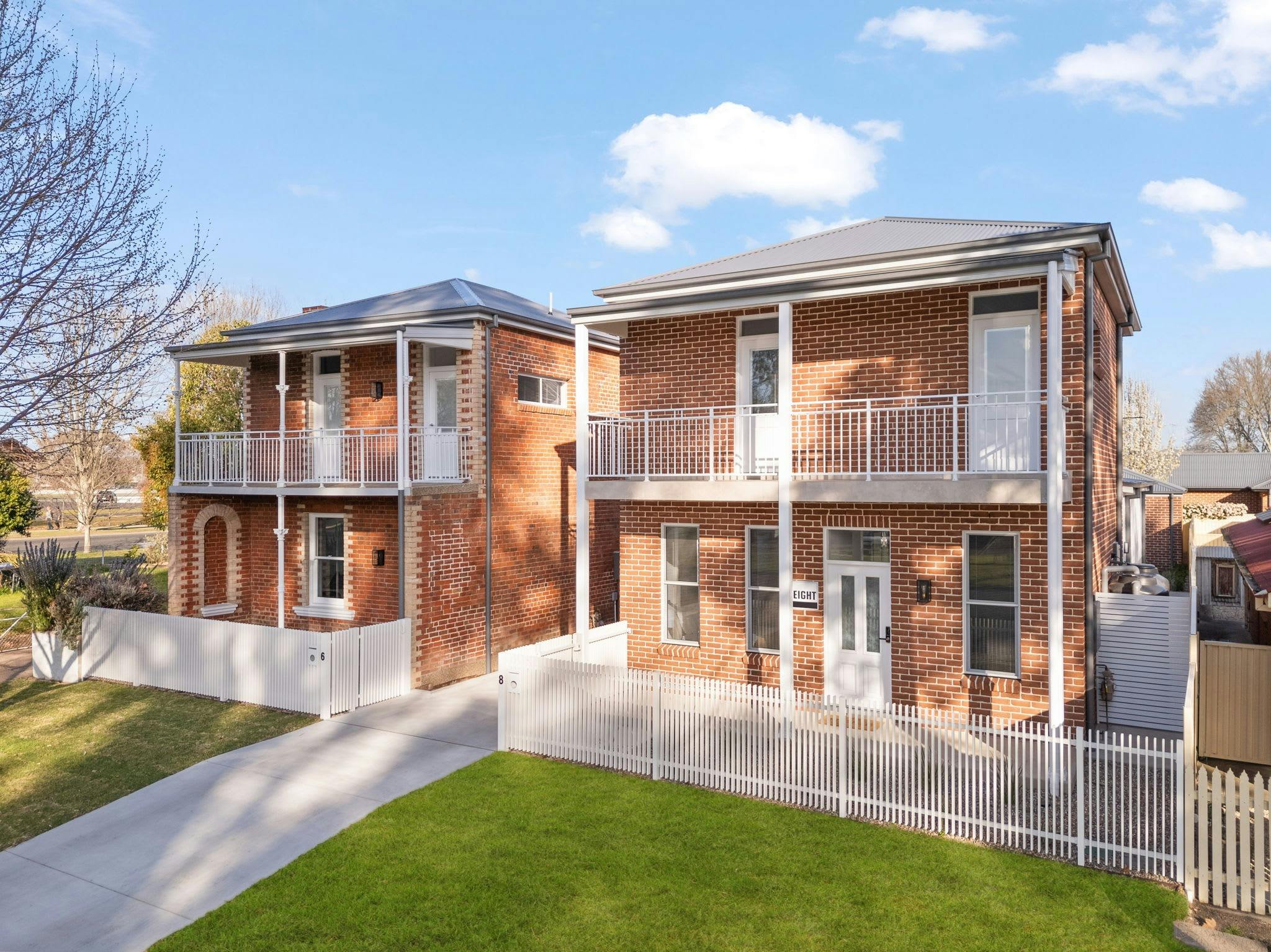 2 Large brick apartments with 2 stories and a concrete driveway running through the middle