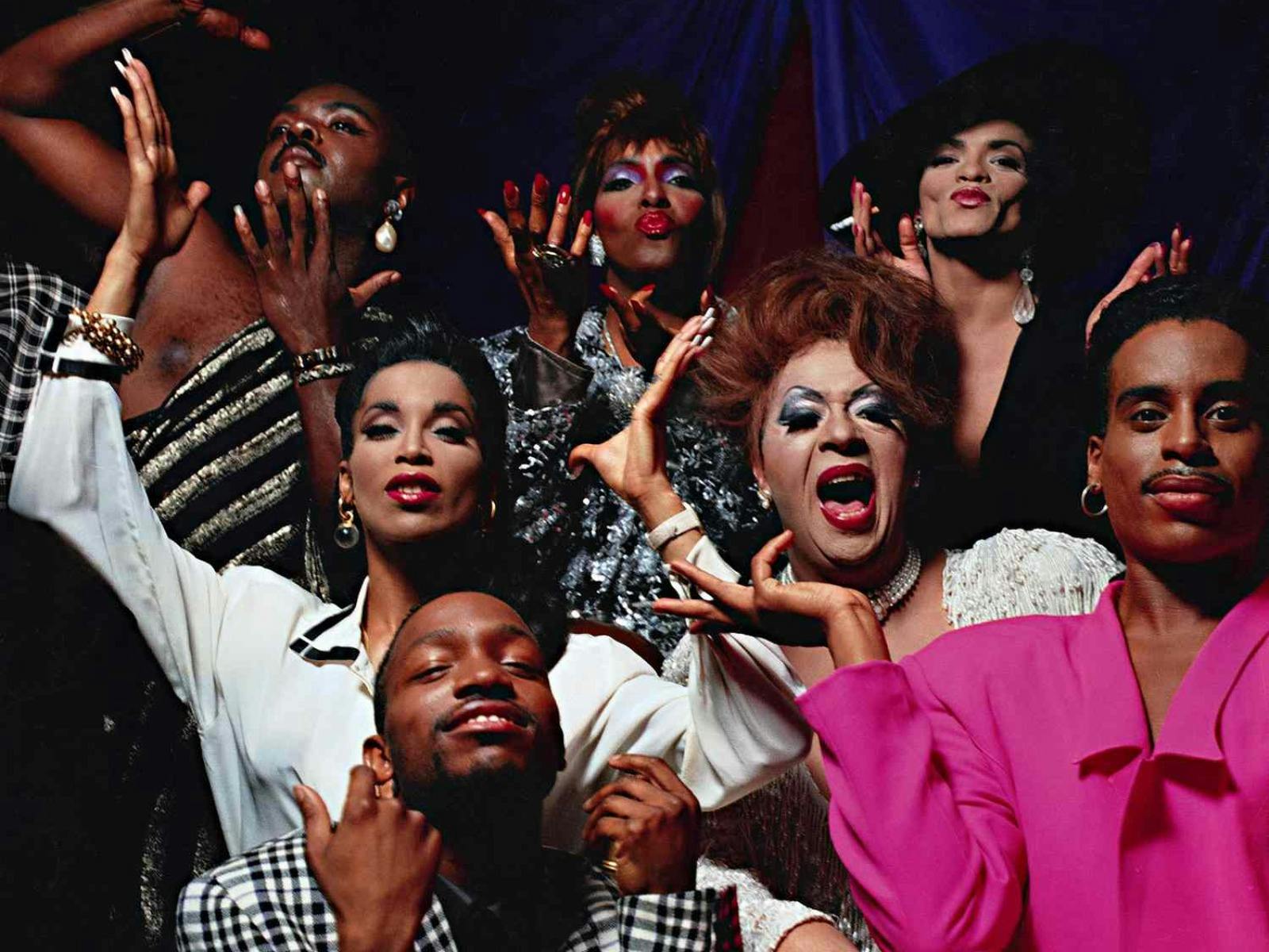 A vibrant group of drag queens and LGBTQ+ performers striking expressive poses.