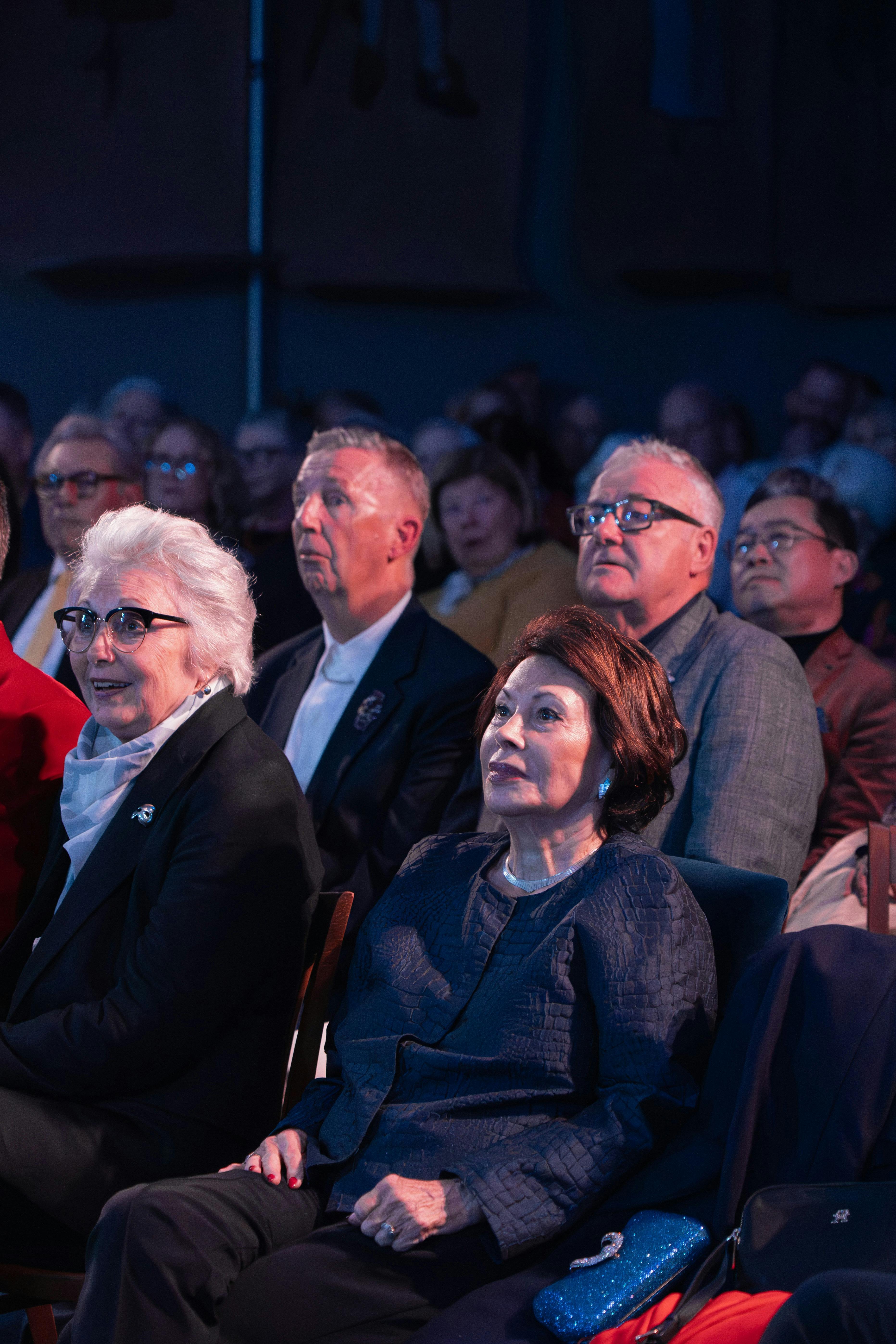 Audience members watch a performance and smile