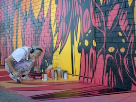 George Rose applying some finishing touches to her super colourful Sturt Desert Pea Mural