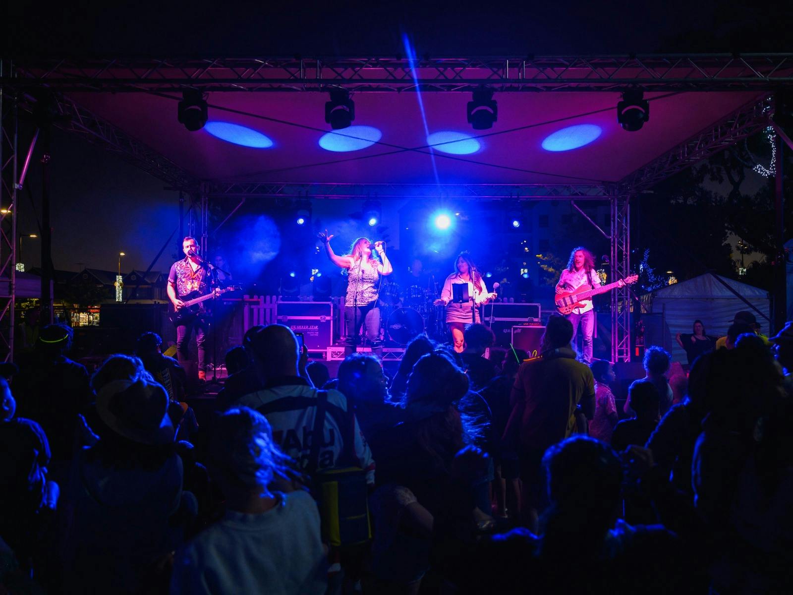 Dark stage lit up with blue lights featuring four performers