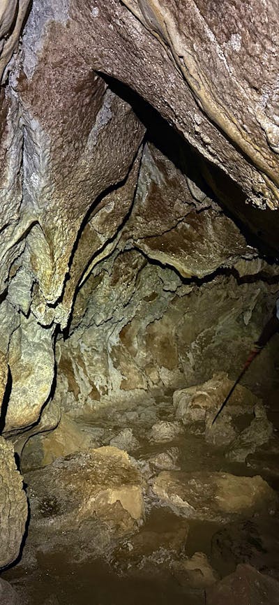 A cave with a tier walking through with a head torch.