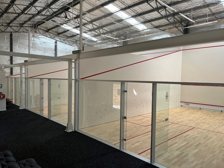wider shot photo of squash court showing three courts