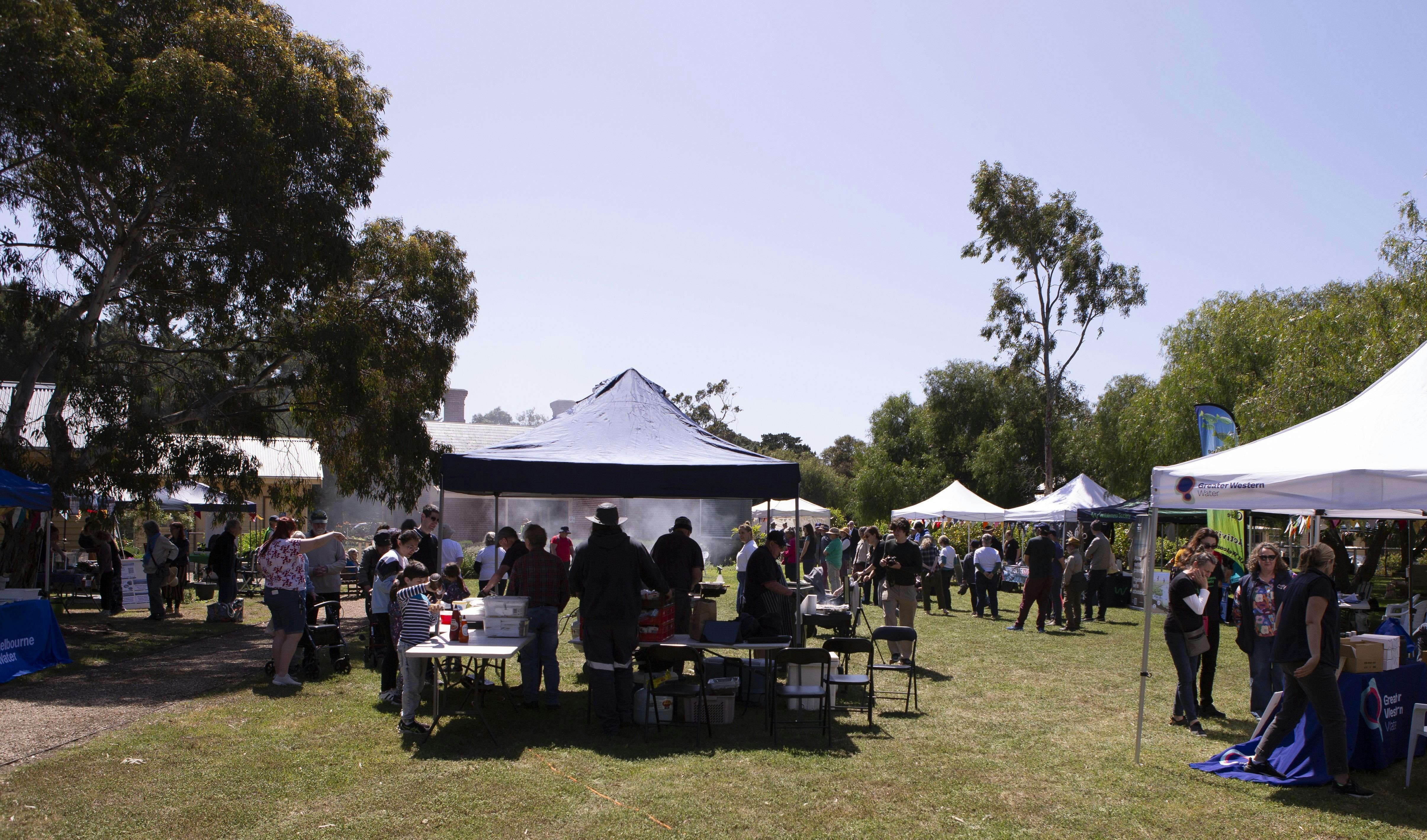 There are around ten marquees with people and activities on a sunny day in the outdoors.