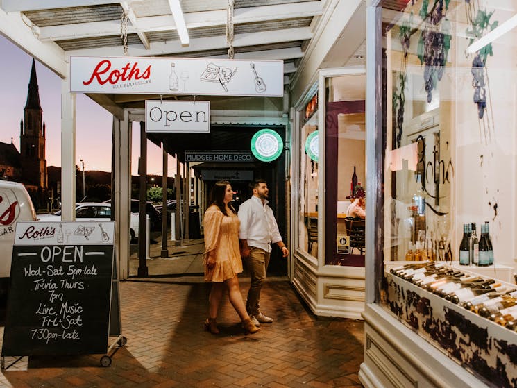 Couple enter Roth's Wine Bar from street at sunset backdropped by church steeple