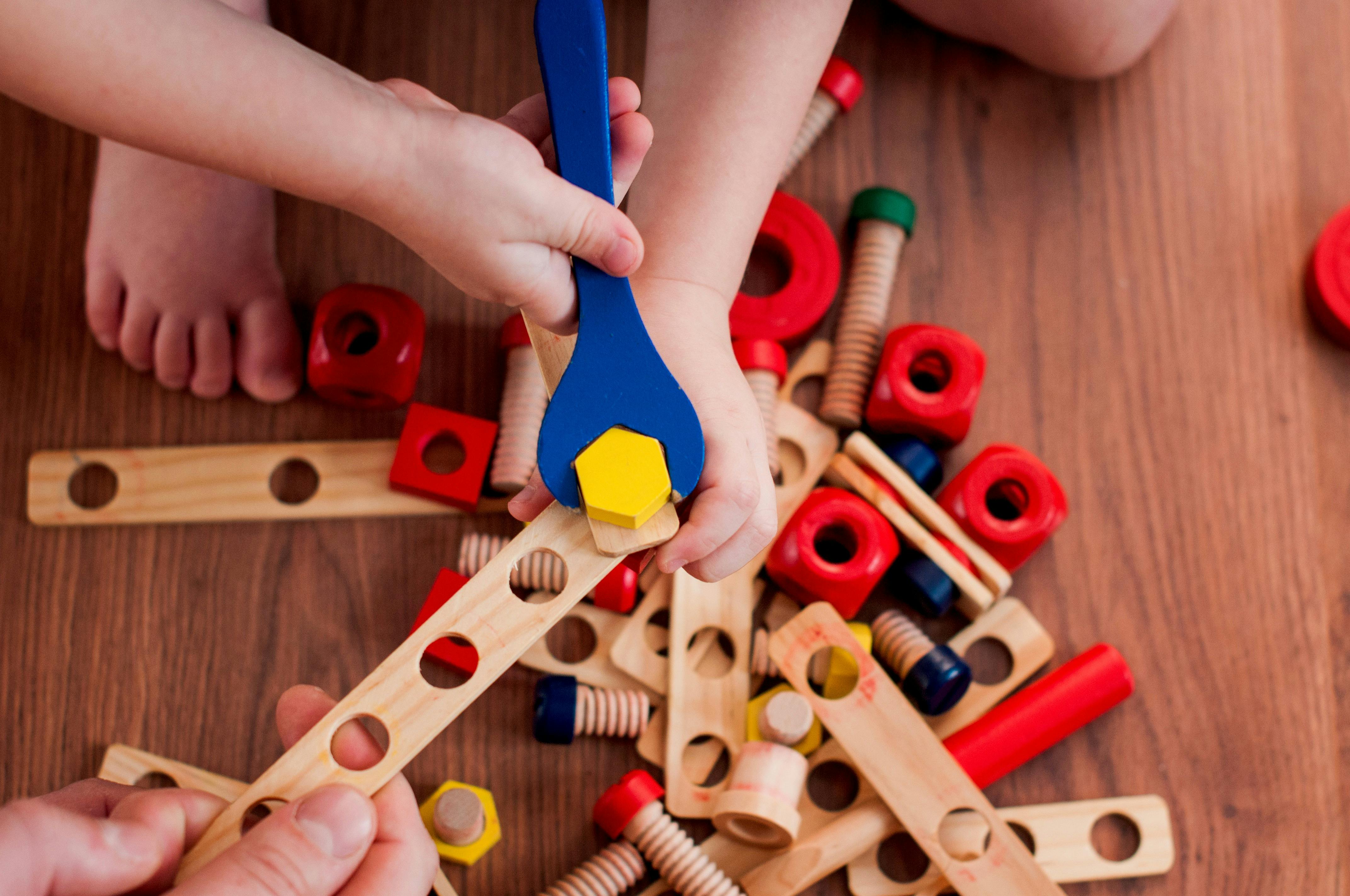 A child uses a wooden spanner to attach pieces together