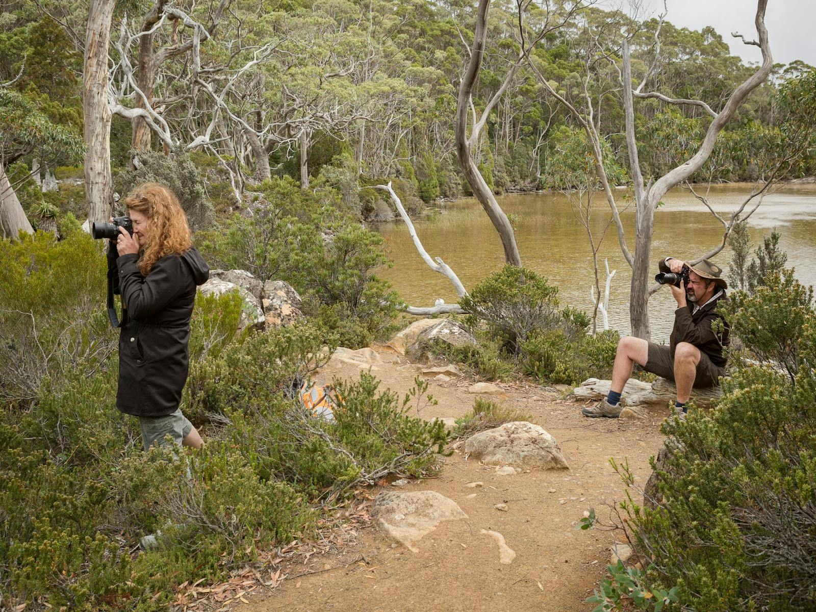 Two guests on private Shutterbug Walkabouts tour, both with cameras in hand, standing in bushland