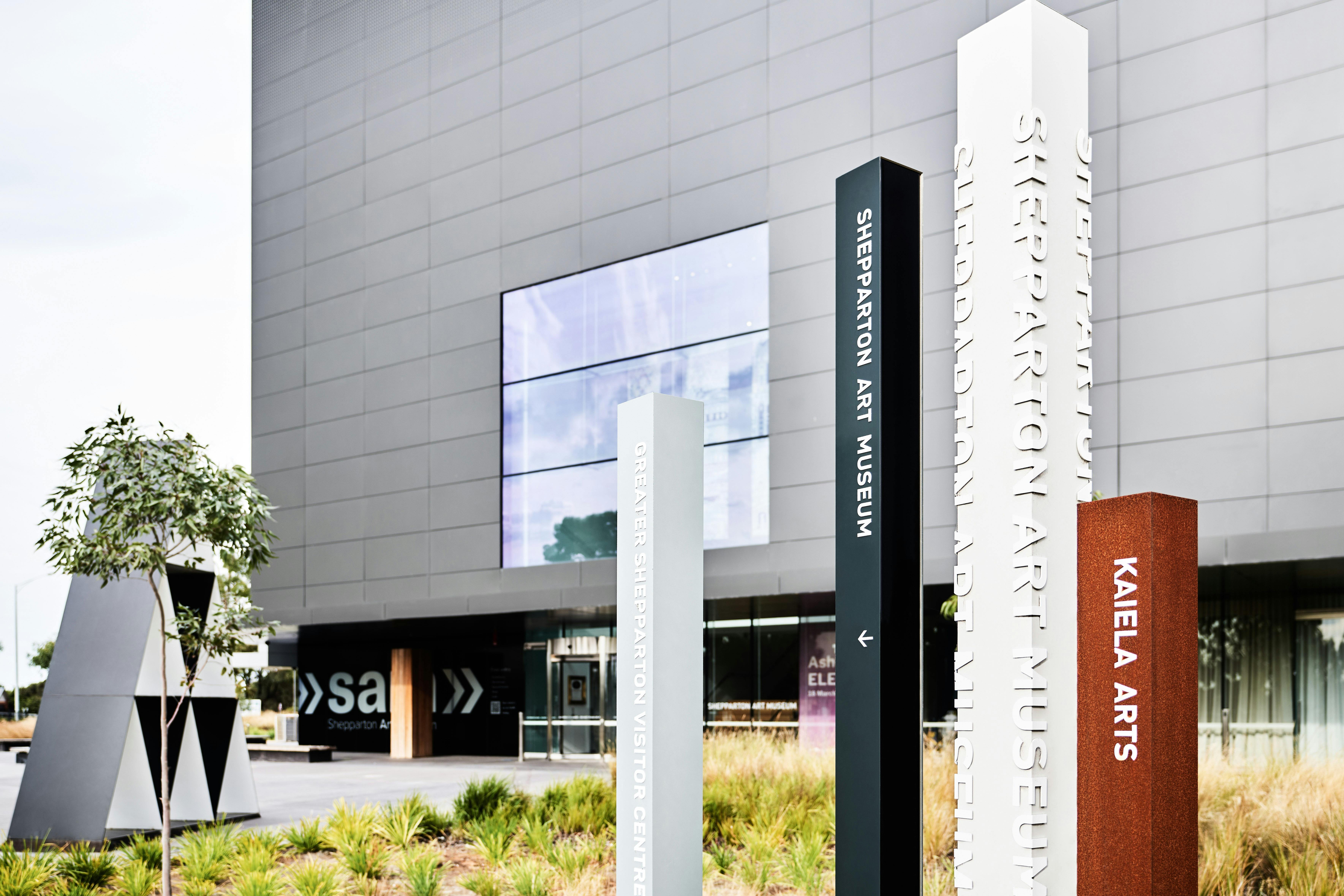Photo of the front facade of SAM - a large,  charcoal-grey cube building with wayfinding signage.