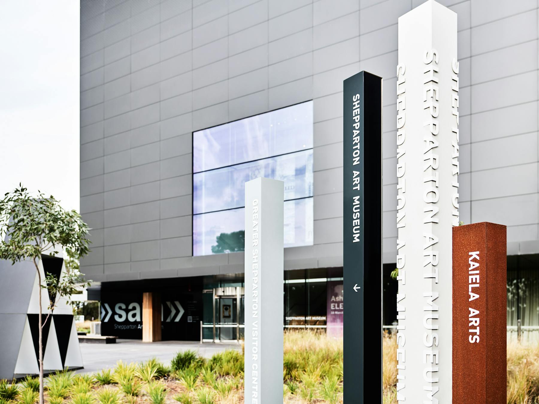 Photo of the front facade of SAM - a large, charcoal-grey cube building with wayfinding signage.