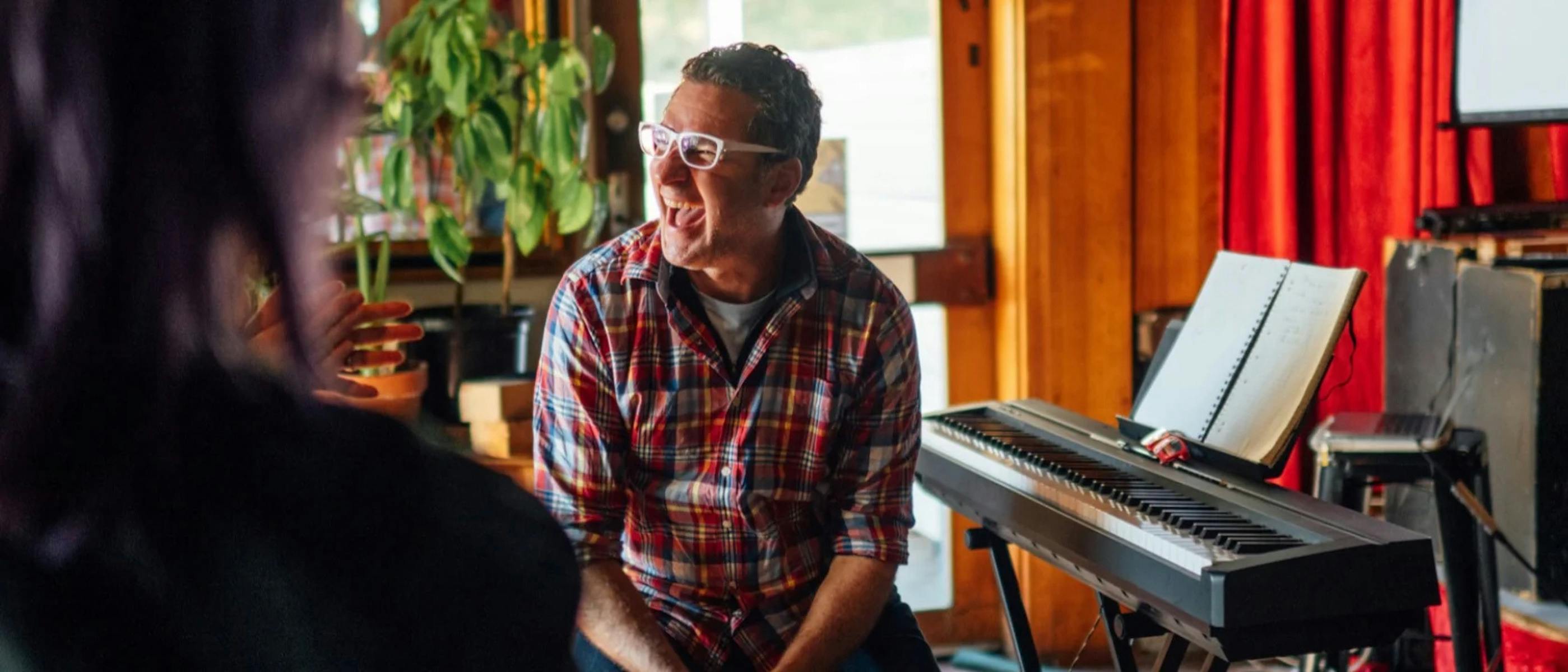 A man laughing sits at a keyboard