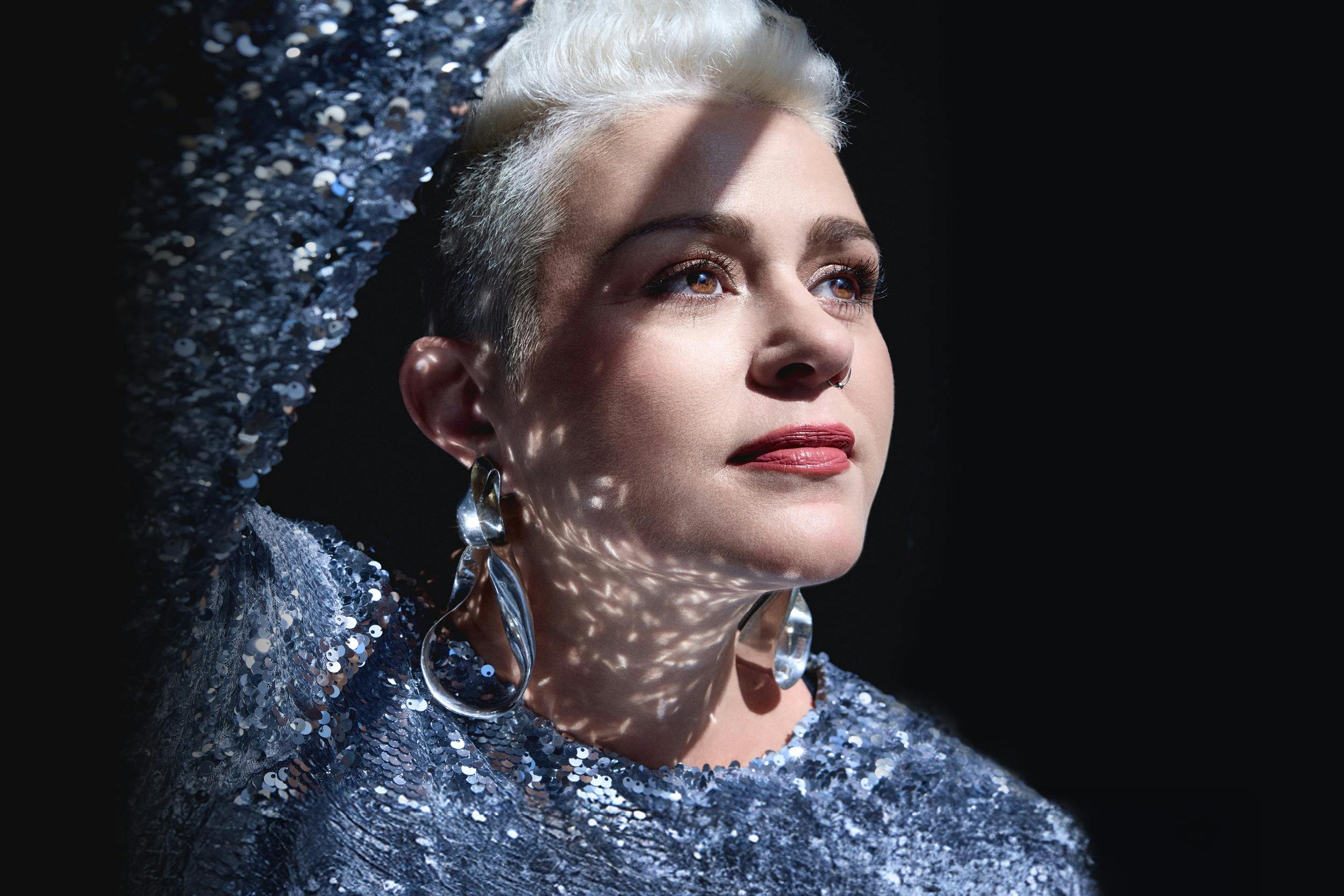 Katie Noonan posing in front of black background.