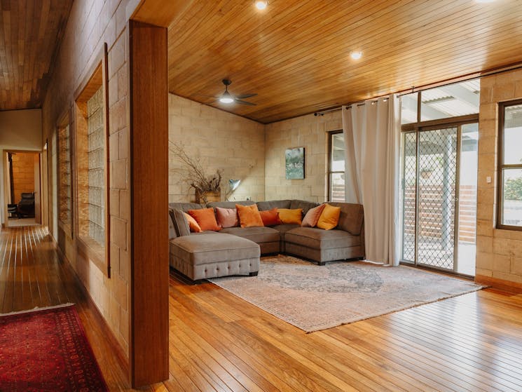 A large L-shaped lounge in a room with timber floors and sliding doors