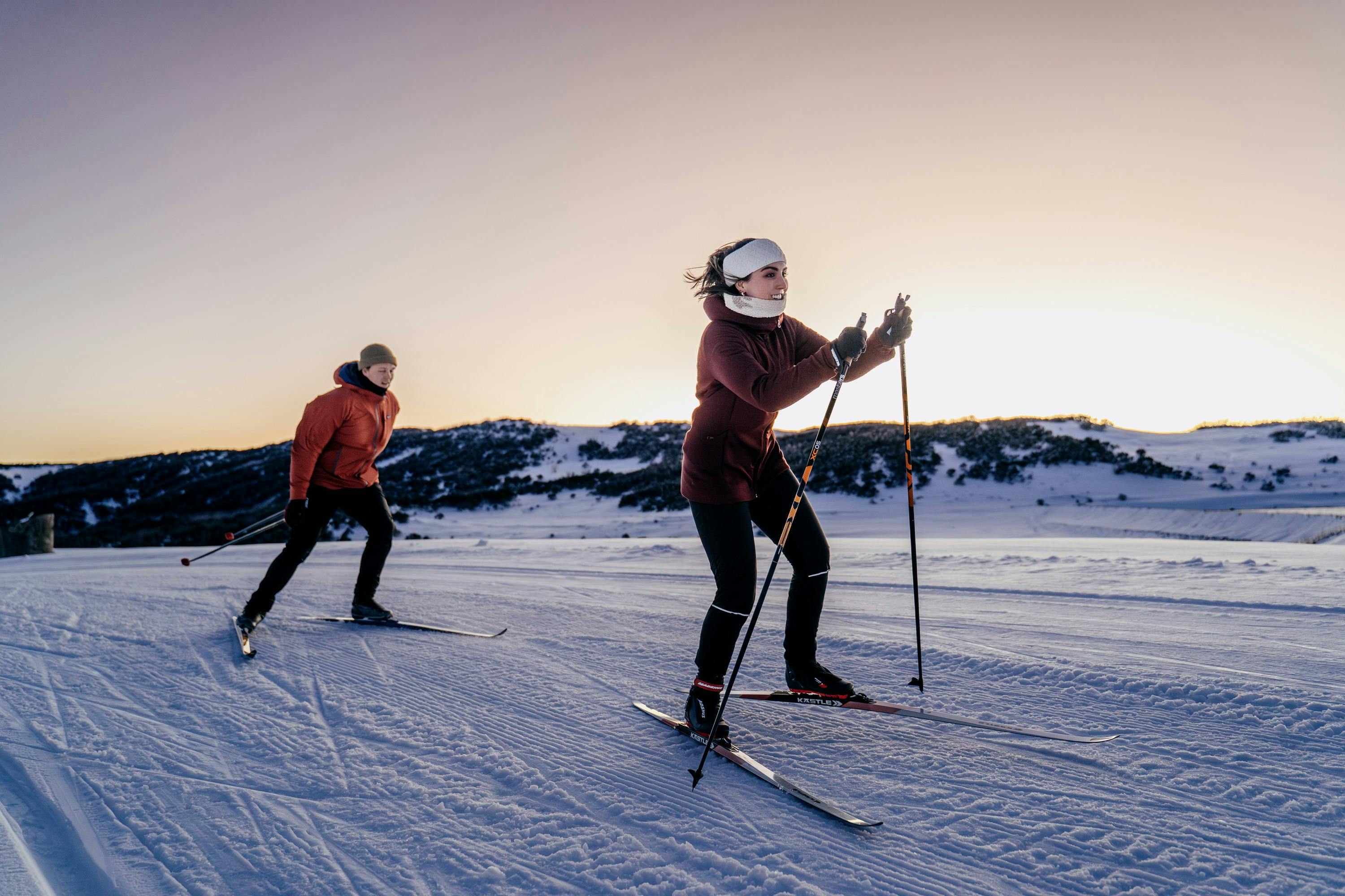 Two people cross country skiing on the High Plains at dawn with mountains surrounding them
