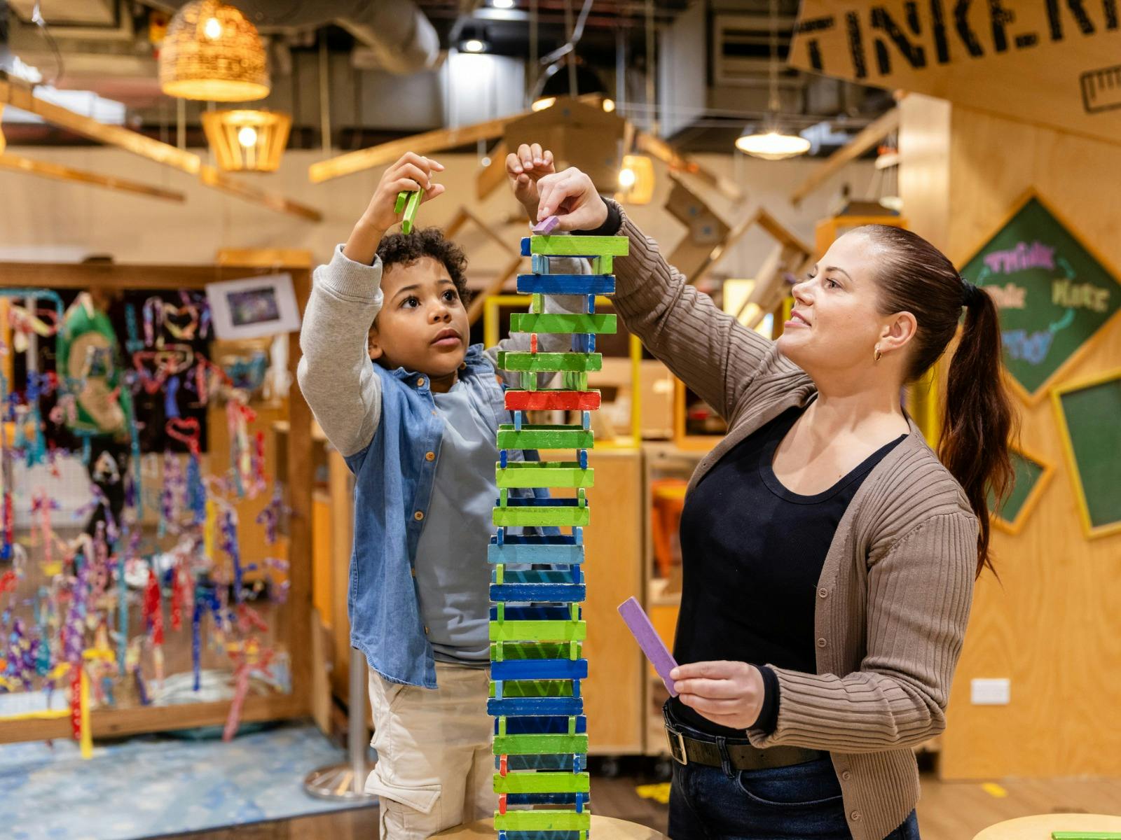 A mother and her child building a tower out of blocks