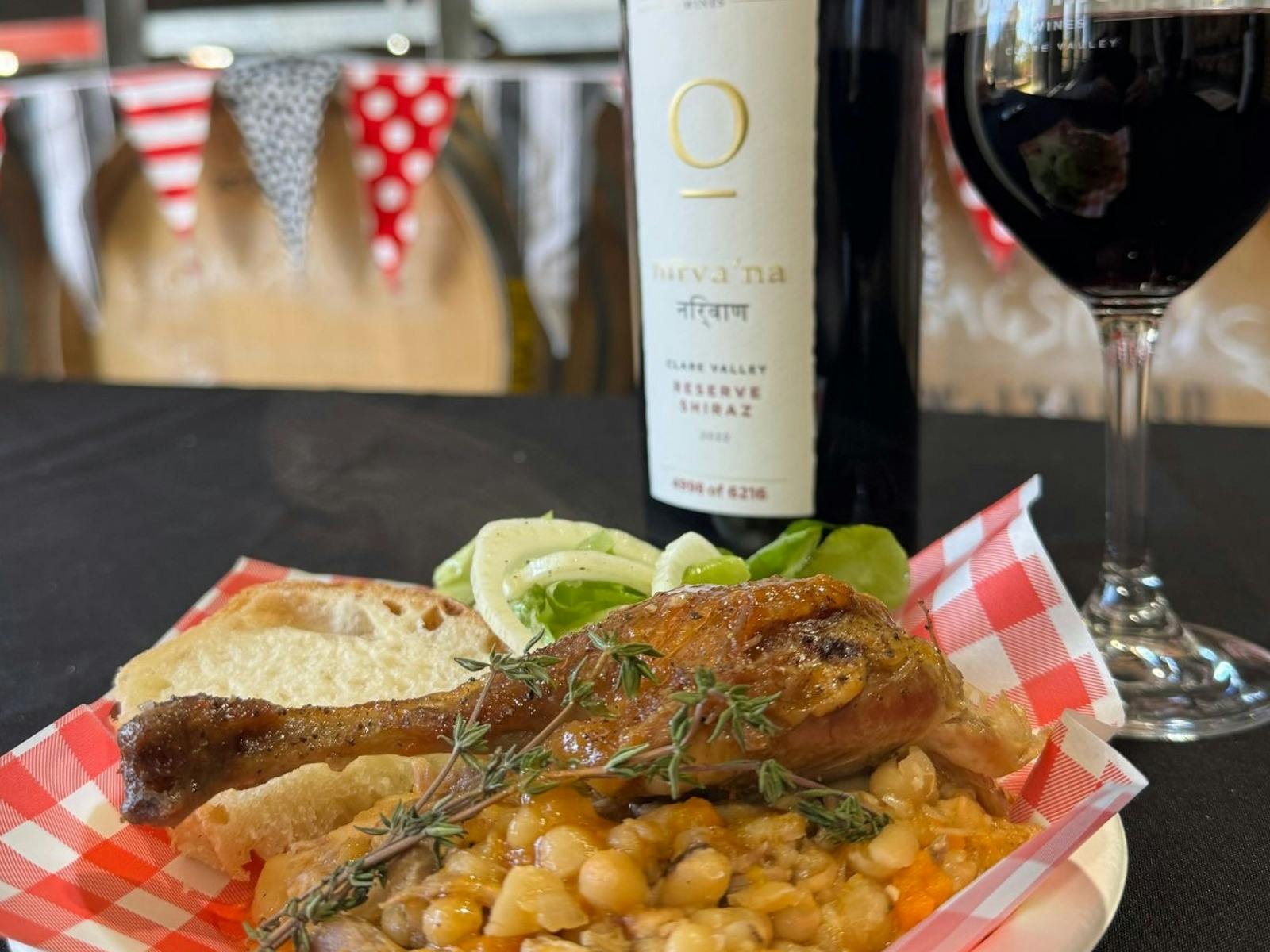 duck cassoulet with beans plated next to a bottle of shiraz and glass of red wine