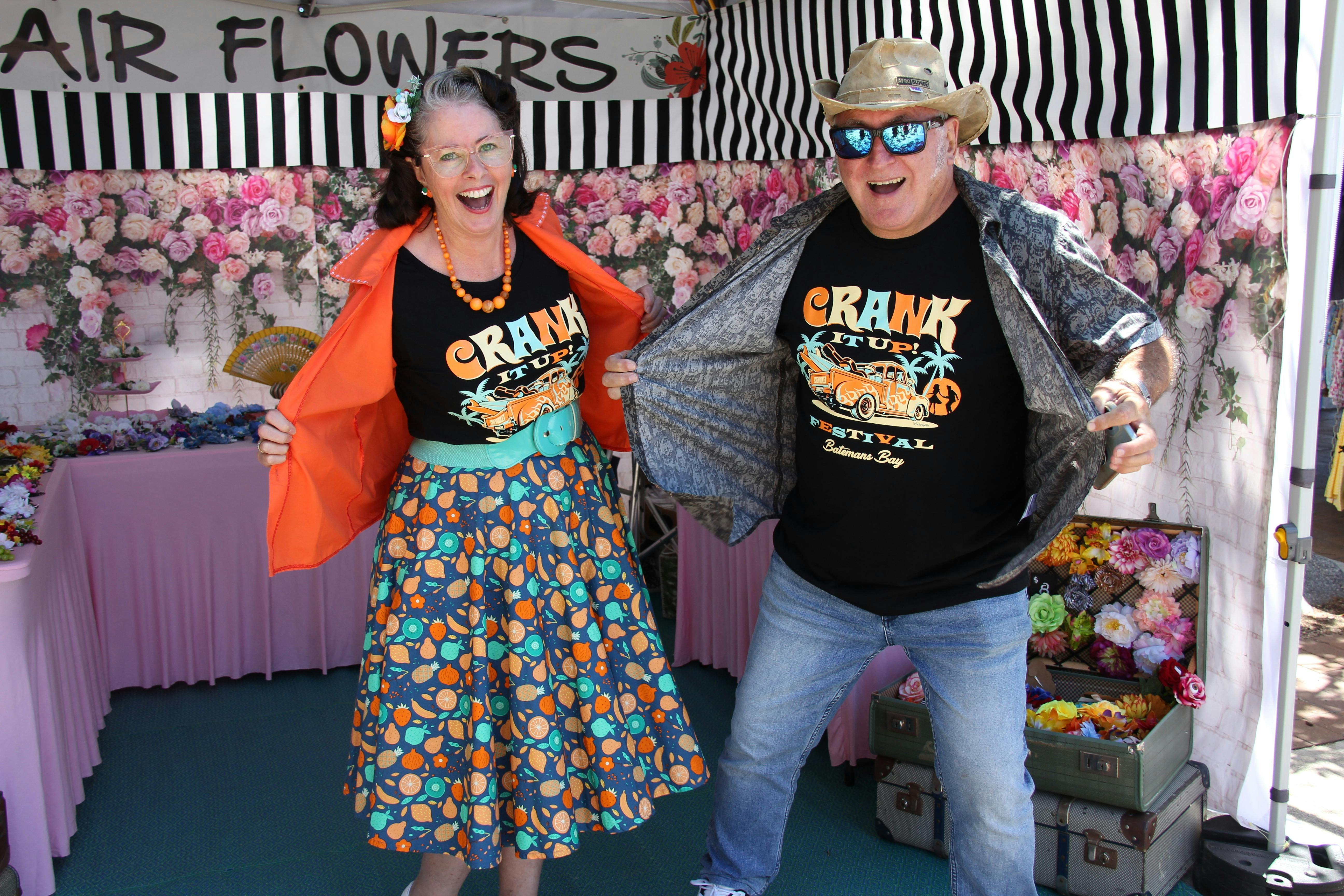 Two people dressed in Crank It Up shirts standing in a market stall