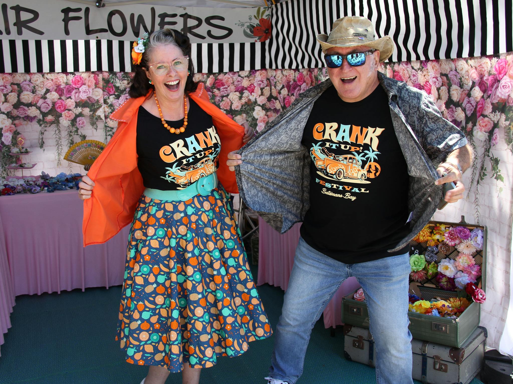 Two people dressed in Crank It Up shirts standing in a market stall