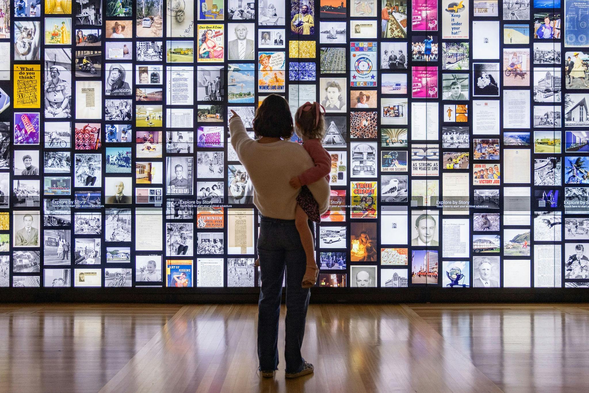 Visitors pointing at interactive digital wall.