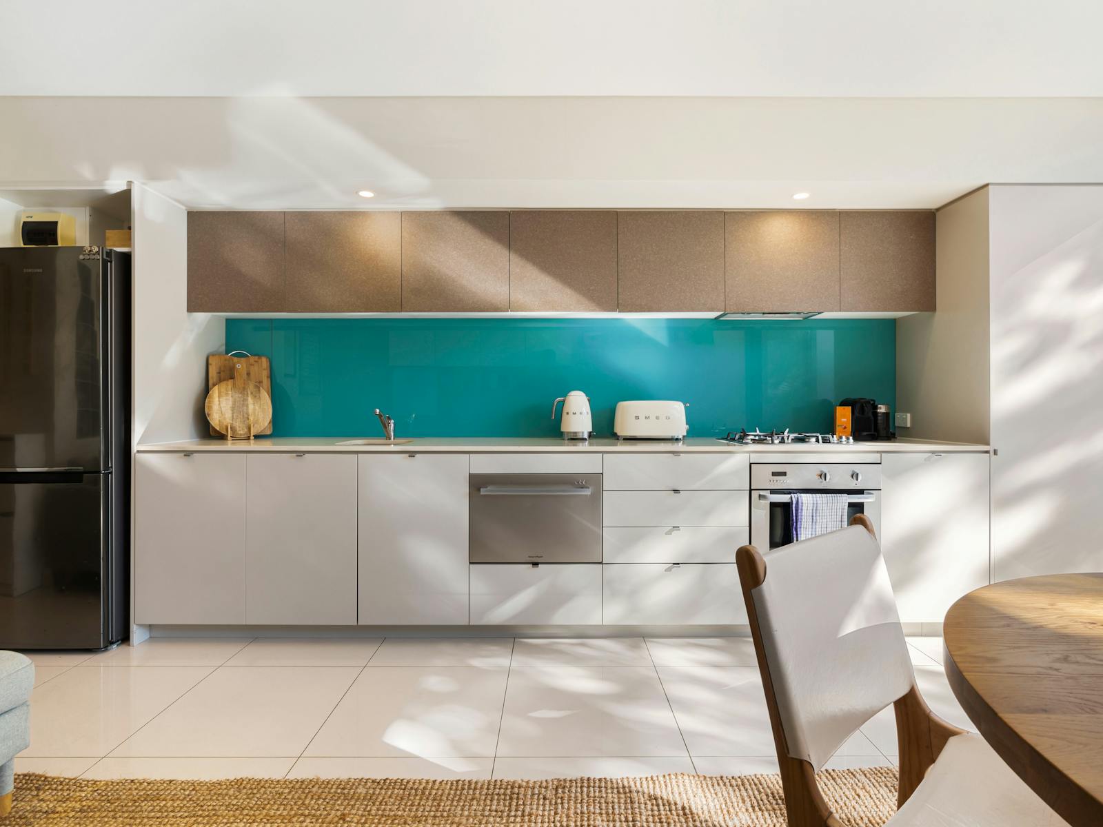 Modern kitchen and living space with a turquoise splashback and a cozy private courtyard.