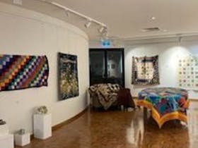 the interior of the Millicent Art Gallery. It has a shiny wooden parquetry floor and white walls.