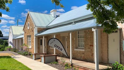 stone building with tin roof in sunshine with open flags