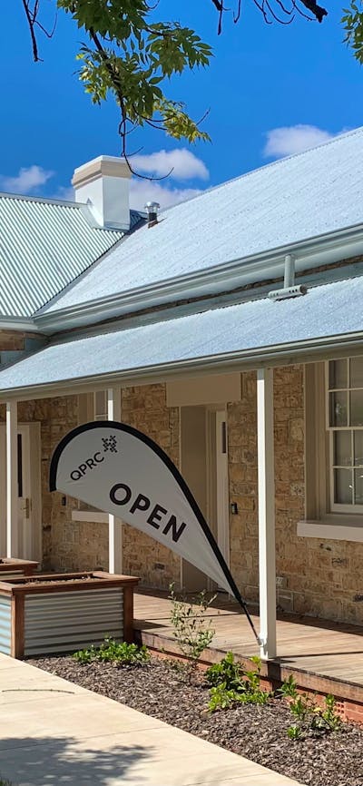 stone building with tin roof in sunshine with open flags