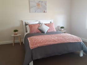 Queen bed, pillows, throw rug 2 side tables, 2 reading lamps, styling items and print on wall