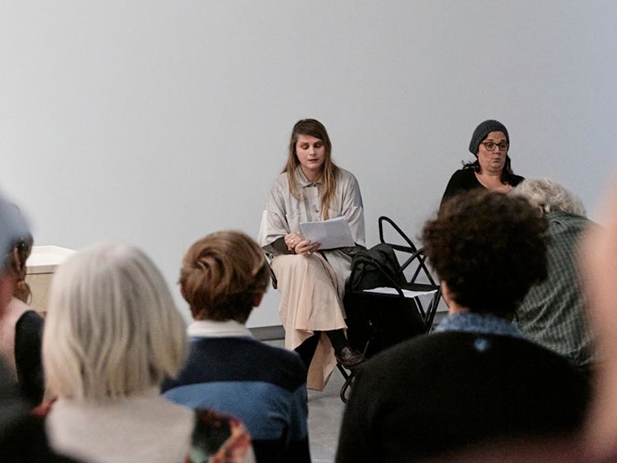 A photo taken from the perspective of the audience as they listen to a poetry reading