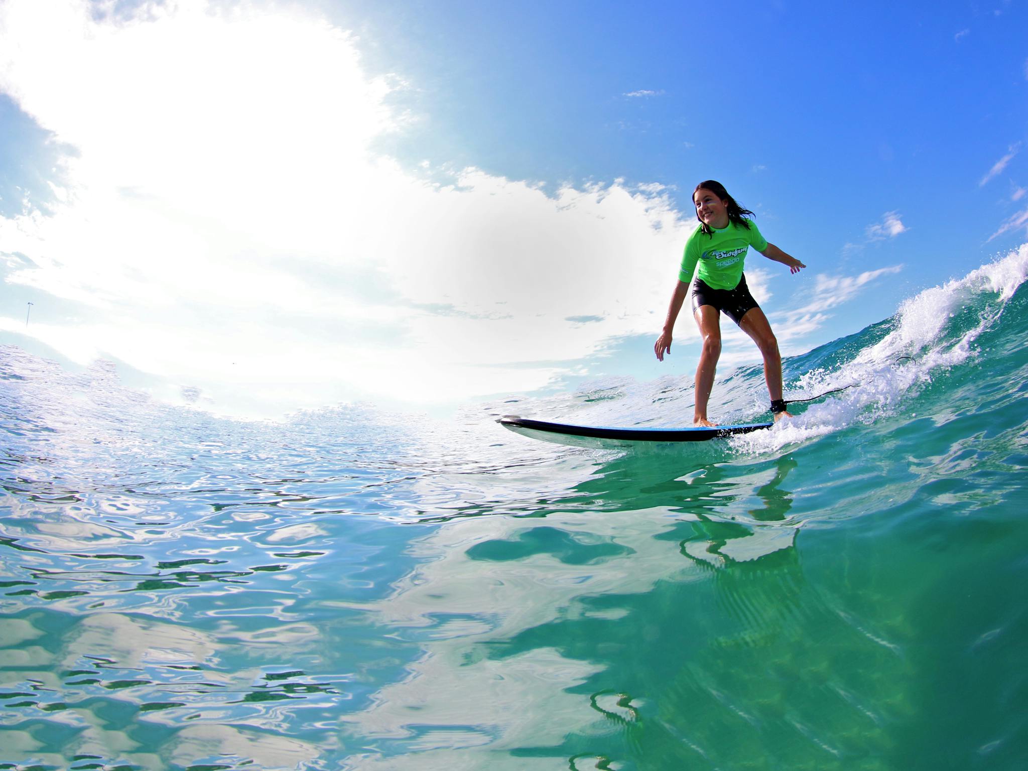 Girl riding a wave in a surf lesson