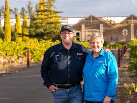 Coonawarra Experiencesu2019 Simon and Kerry Meares standing in a vineyard at golden hour.