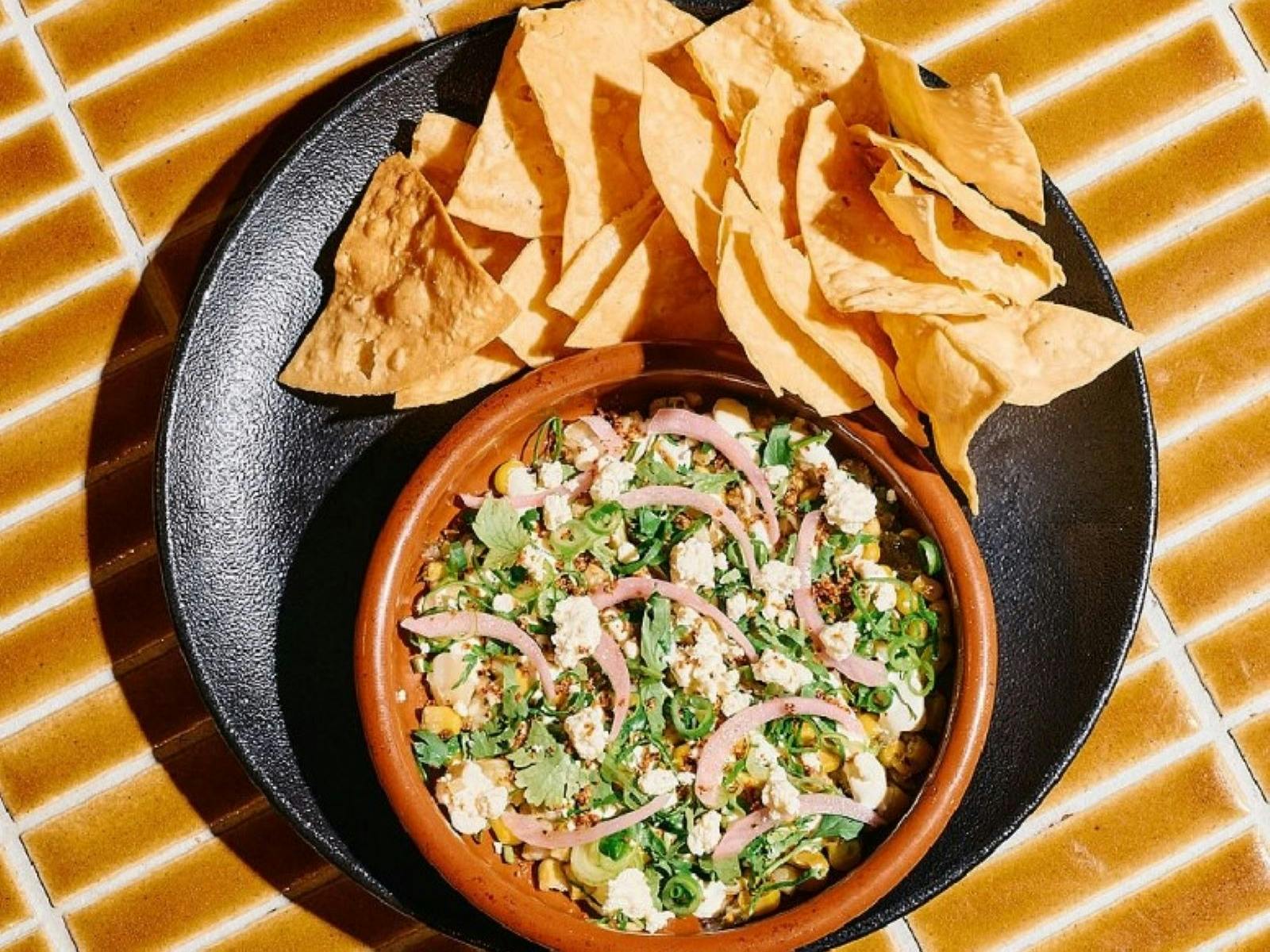 Image of a plate of Mexican food with nachos chips on the side