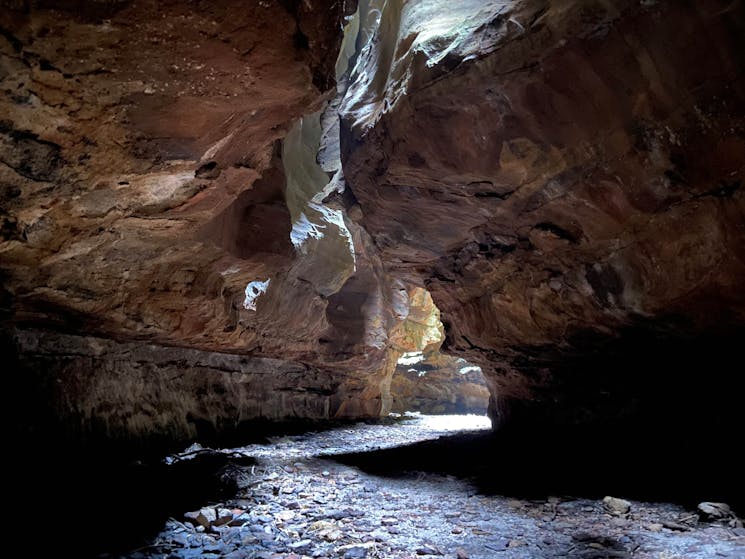 A dark incised sandstone  slot canyon with sunlight streaming  down from above