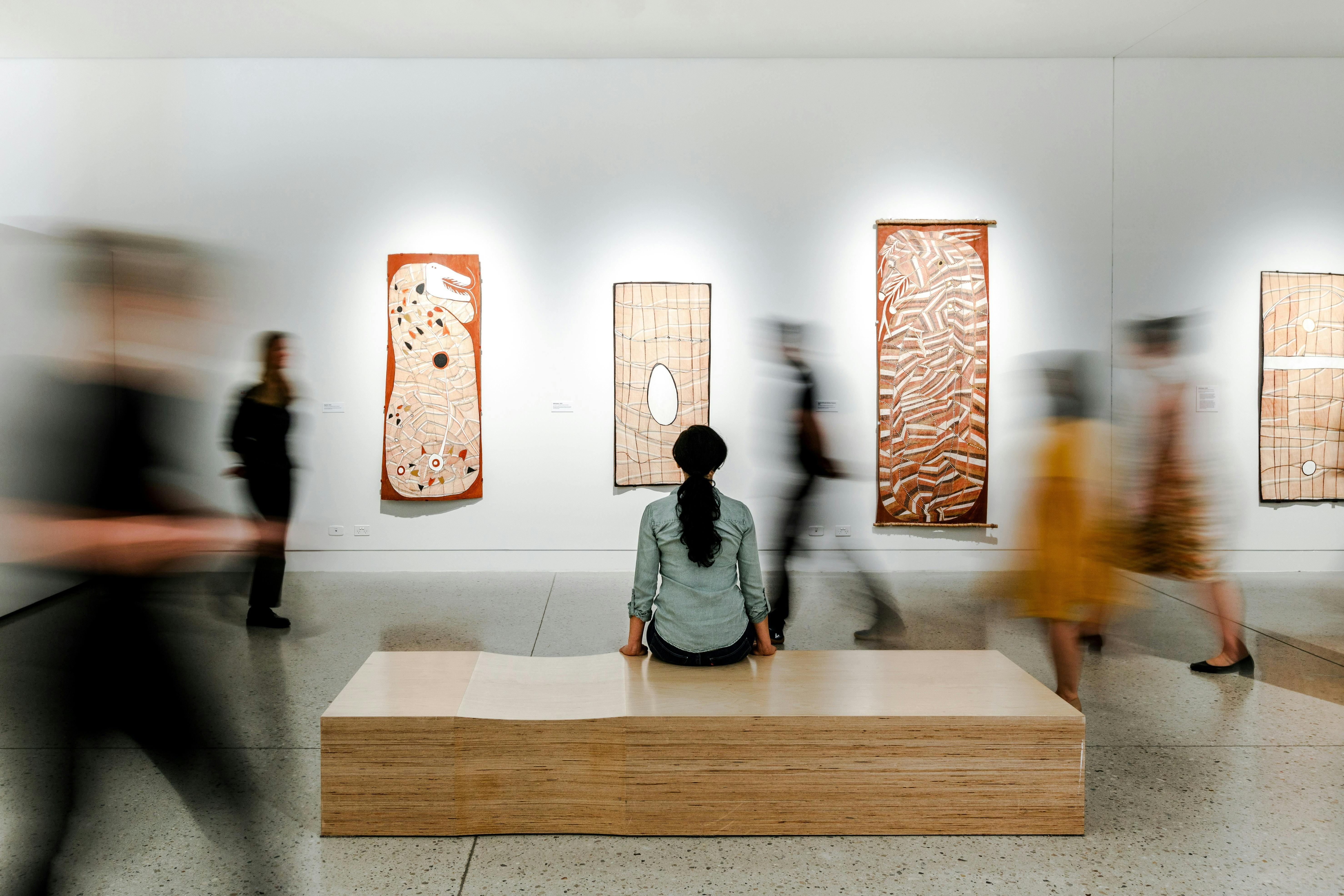 Woman sitting an admiring art in an open space gallery