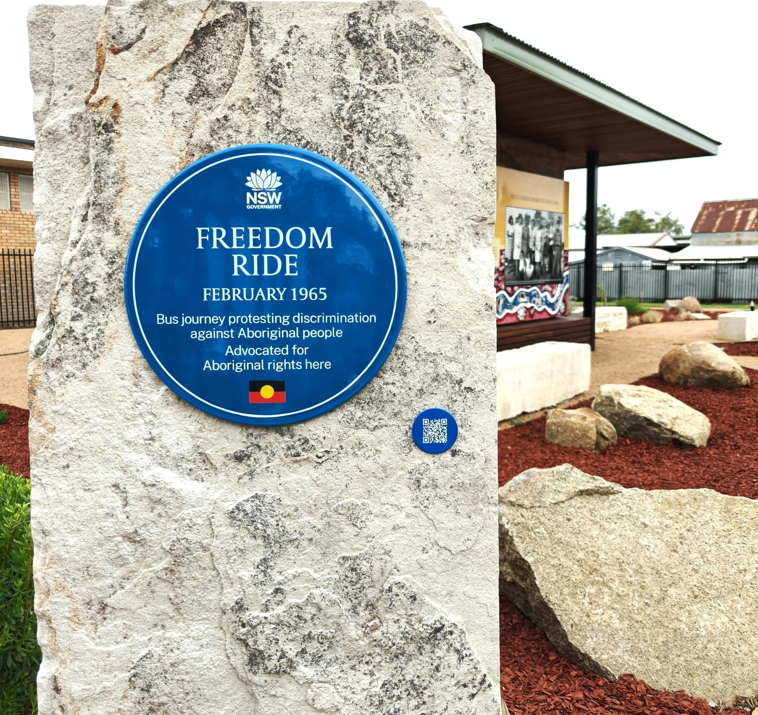 Blue plaque on stone plinth in park setting