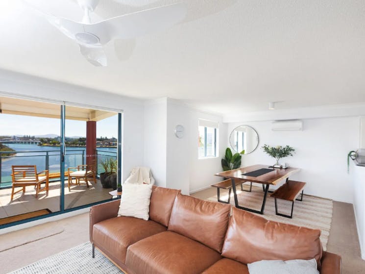 Living area with modern coastal decor and furnishings, leading out to balcony