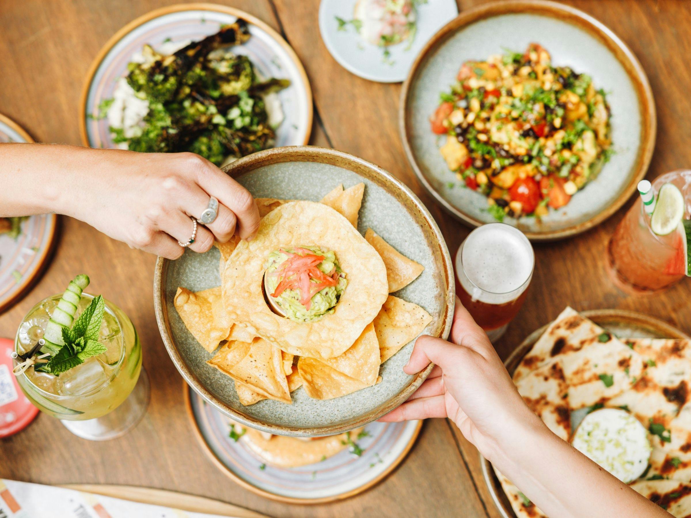 Friends passing food across the table at The Yard