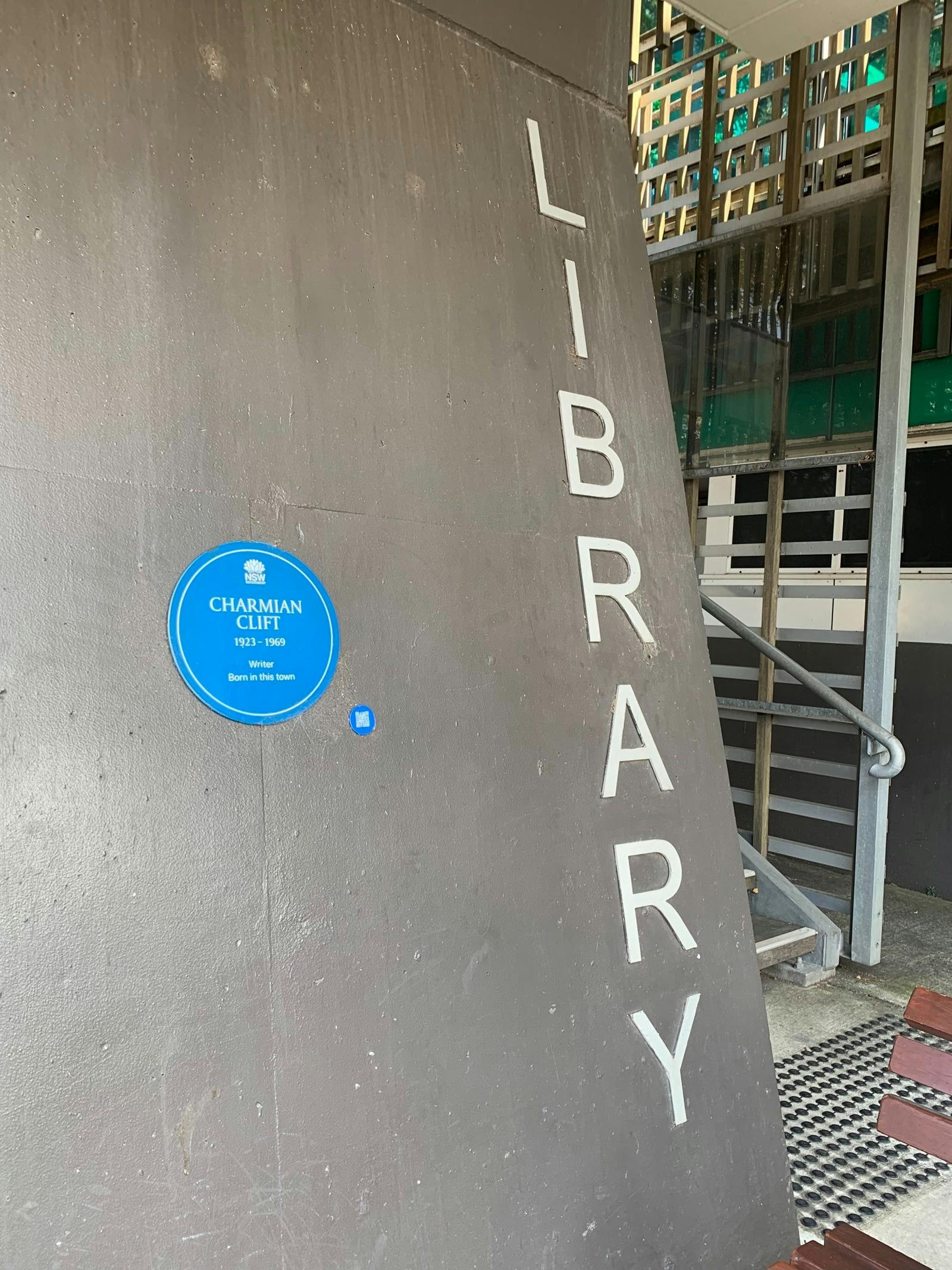 Blue plaque and QR code on dark grey wall next to lettering that says 'Library'