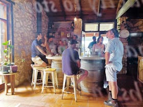 A group of visitors enjoying a relaxed wine tasting experience around a stone barrel table inside th