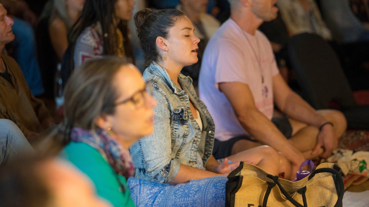 Group of people meditating, singing, eyes closed
