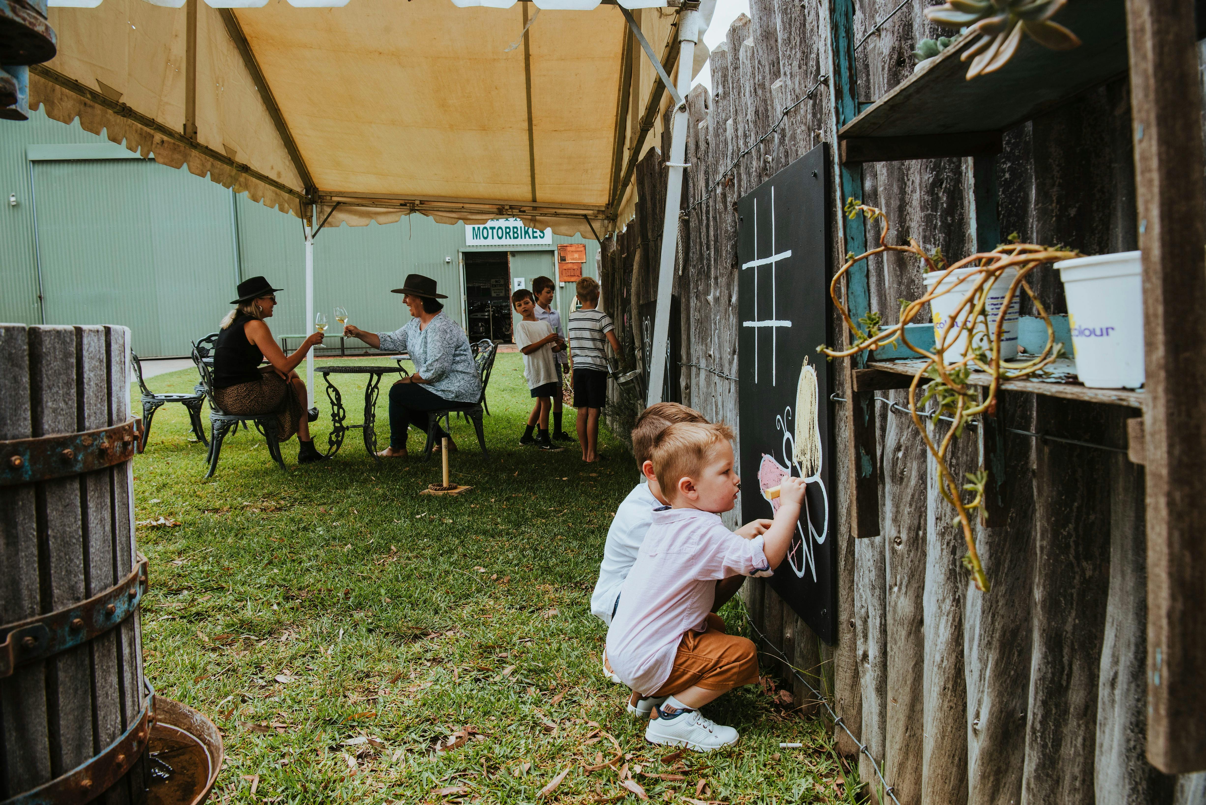 가족 와인 시음 칠판에 그림을 그리는 아이들 뒤에서 와인을 시음하는 엄마들
