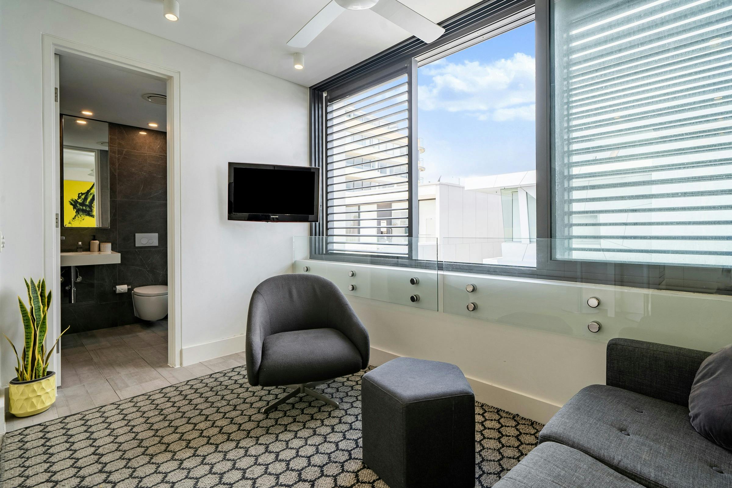 Contemporary living space with kitchen, lounge, and large windows offering natural light.