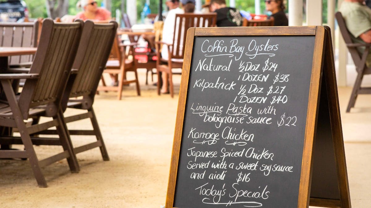 A-frame chalkboard outside Dingo Beach Pub displaying daily food specials including local seafood