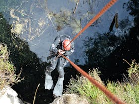 Diver descending by rope into hells hole