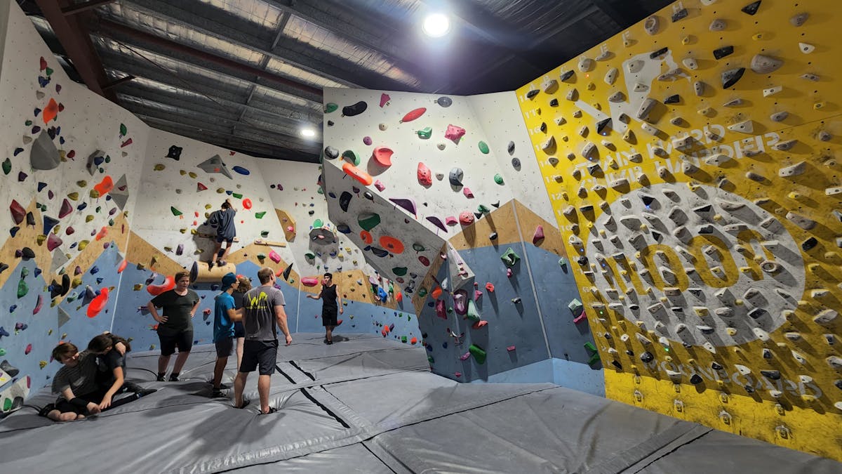 A lot of climbers standing on the climbing mat with some people climbing on the wall at Wall Walkers A lot of climbers standing on the climbing mat with some people climbing on the wall at Wall Walkers