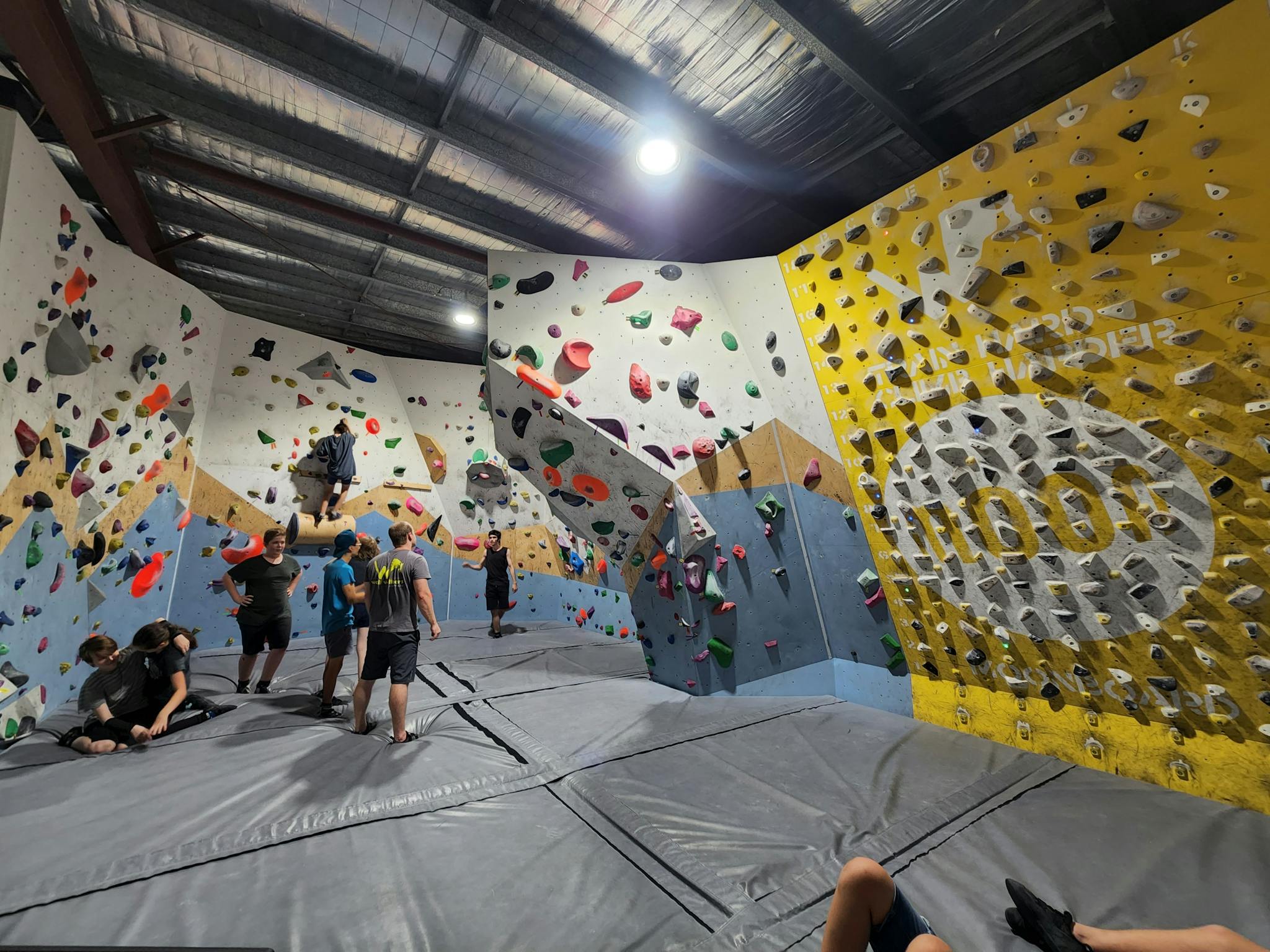 A lot of climbers standing on the climbing mat with some people climbing on the wall at Wall Walkers A lot of climbers standing on the climbing mat with some people climbing on the wall at Wall Walkers
