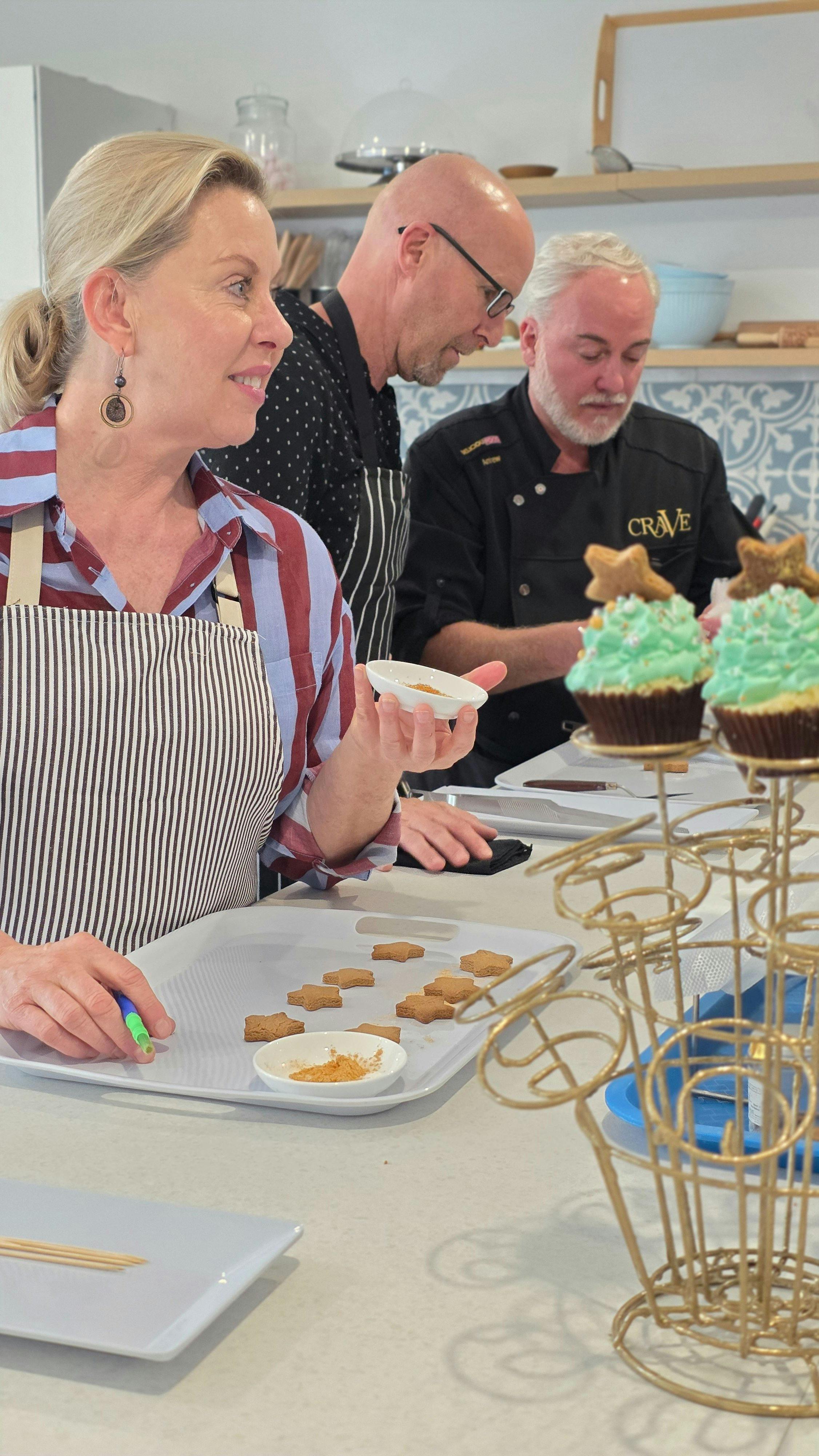 students in a owrkshop in Crave School kitchen, one woman is painting cookies